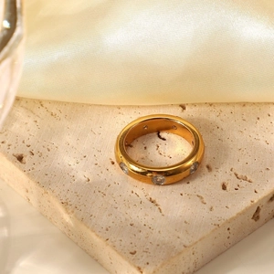 Macro shot of gold ring with round clear zircon stones on textured stone surface