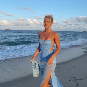 Detail of light blue backless maxi dress with side split and pleated fabric on beach