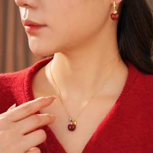 Primo piano del set collana e orecchini a mela rossa in oro 18k placcato su modella