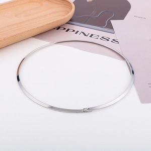 Close-up of minimalist silver stainless steel flat collar necklace on wooden tray