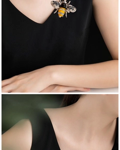 Detail of bee brooch with yellow enamel and rhinestones shown on a black V-neck garment
