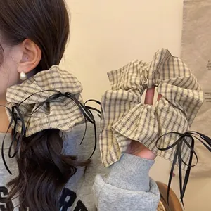 Preppy style beige plaid scrunchie with black ribbon bow for elegant low ponytail styling