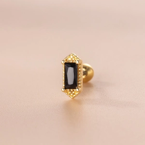 Makroaufnahme von goldfarbenem Edelstahl-Ohrstecker mit rechteckigem schwarzem Zirkon