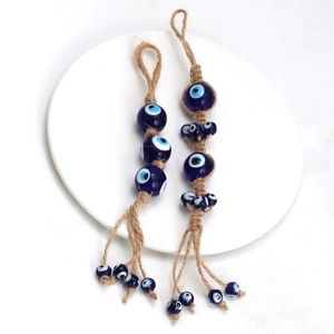 Handmade Evil Eye charm with blue beads and jute rope on a minimalist white plate
