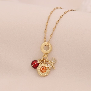 Golden necklace with ladybug sunflower and dragonfly pendants on beige fabric background