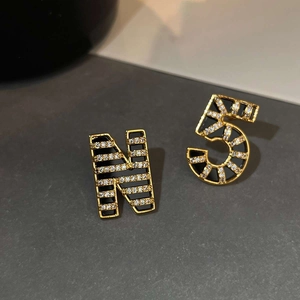 Macro detail of 18K gold plated asymmetric earrings with letter N number 5 and crystals