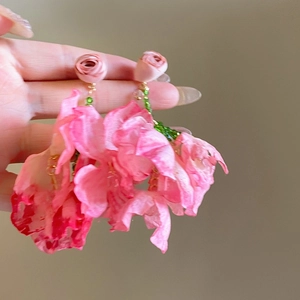 Close-up of handmade pink chiffon flower earrings with green beaded tassels and gold metal hooks