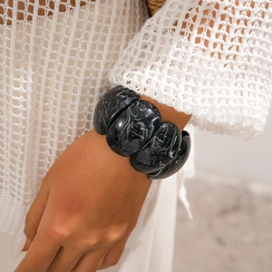 Detailed view of chunky resin bangle featuring black marble texture on a female wrist