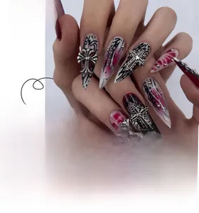 Detail of gothic stiletto fake nails with red black gradient and metal crosses