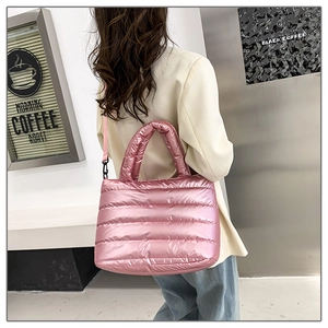 Padded quilted tote bag in bright pink metallic finish shown as a shoulder bag on model