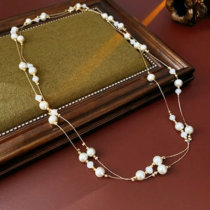 Detail of vintage layered pearl necklace with gold chain on a green velvet base
