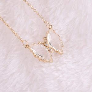 Close-up of golden butterfly pendant with transparent wings and sparkling crystals