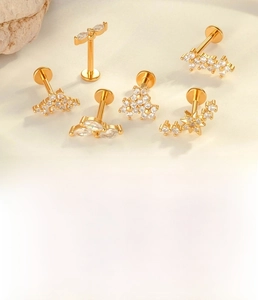 Macro detail of F136 titanium flower stud earrings set with zircon stones in gold and silver