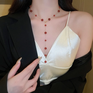 Detailed view of long Y-shaped gold necklace with red agate beads on a professional model