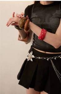 Close-up of retro wooden bangles with studs and floral crystal belt chain on model