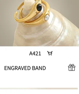 Detail of retro gold open rings featuring black gemstone and white pearl on a conch shell
