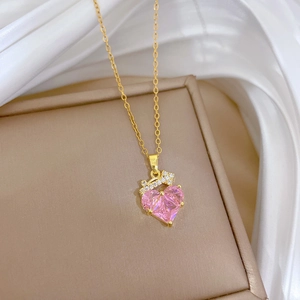 Close-up of golden crown heart pendant with pink zircon on a soft silk background