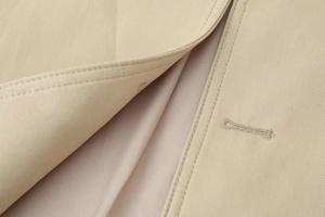 Macro shot of khaki trench coat twill fabric showing fine stitching and buttonhole details
