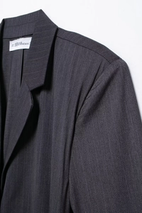 Detailed close-up of dark grey pinstripe blazer fabric with notch lapel and shoulder seams