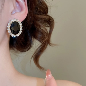 Close-up of vintage oval black gemstone earrings with sparkling crystal halo on model