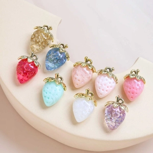 Macro shot of colorful acrylic strawberry pendants with gold loops on a display stand