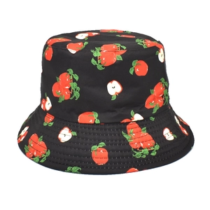 Detailed close-up of a black bucket hat with vibrant red apple and leaf print