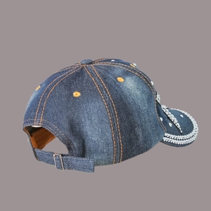 Detail of blue denim baseball cap with silver metal buckle and white stud decorations