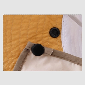 Détail du tissu matelassé jaune avec maille blanche et bouton-pression en métal