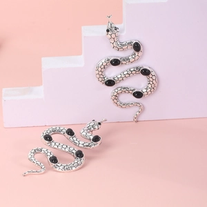 Macro shot of silver snake earrings with black gemstone inlays and scale texture