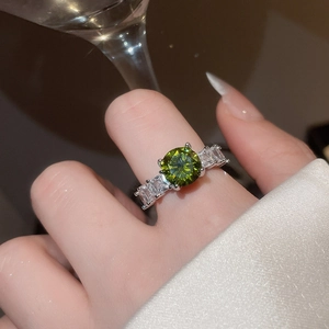 Close-up of green round zircon ring with side baguette stones on a model's hand