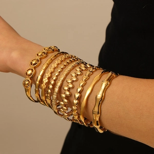 Ensemble de bracelets dorés superposés avec motifs bambou et cœur sur le bras