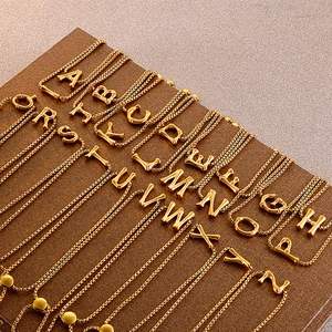 Golden stainless steel A-Z alphabet bracelets set displayed on brown leather texture