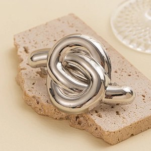 Close-up of a silver twisted knot metal hair ring on a textured stone display