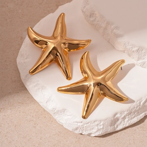 Detailed close-up of golden starfish earrings on a white stone base with metallic shine