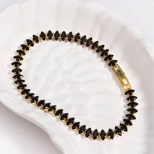 Detail of a golden tennis bracelet featuring black marquise-cut zircons in a shell bowl