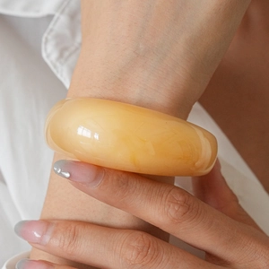 Close-up of amber resin bangle showing translucent warm yellow texture and glossy finish