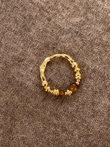 Detail of 18K gold plated tiger eye ring on a brown knit sweater background