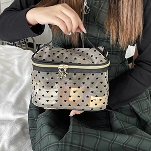 Detail of black heart print mesh makeup bag with star zipper pull and top handle
