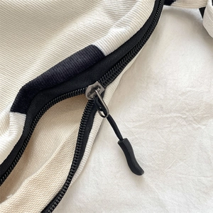 Detail of black zipper closure and corduroy fabric texture on cow print crossbody bag