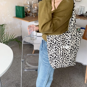 Close-up of a leopard print canvas tote bag styled with a green knit sweater and denim