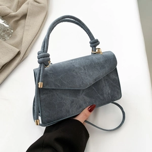 Sac bandoulière bleu en jean avec poignée et boucle dorée sur fond minimaliste