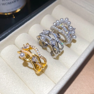 Macro shot of 18k gold and silver wave rings with sparkling zircons and white pearls