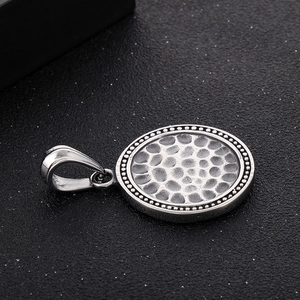 Detailed macro view of silver stainless steel pendant with hammered texture and beaded edge