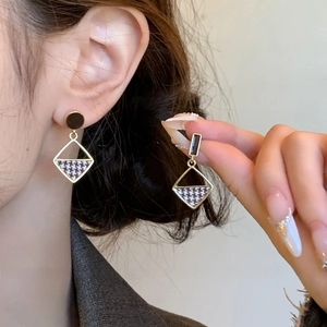 Vintage geometric diamond earrings with houndstooth pattern and golden finish on model