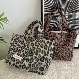 Detailed view of two leopard print plush tote bags in tan and pink faux fur textures