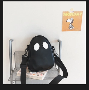 Detail view of ghostly PU leather crossbody bag featuring white oval eyes on mesh display
