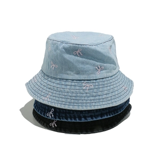 Three denim bucket hats in light blue, dark blue, and black with pink bow embroidery
