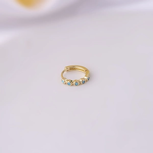 Detailed view of a gold-plated hoop earring featuring five turquoise-colored stone insets