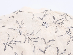 Close-up of embroidery details and cotton-linen texture on the back of a beige V-neck blouse