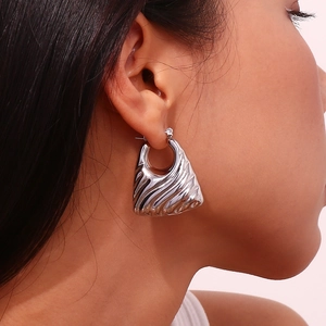 Modern wavy geometric hollow earrings in silver finish shown on a model side profile